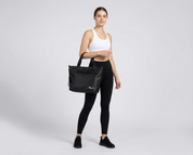 Woman holding a black tote bag against a white background