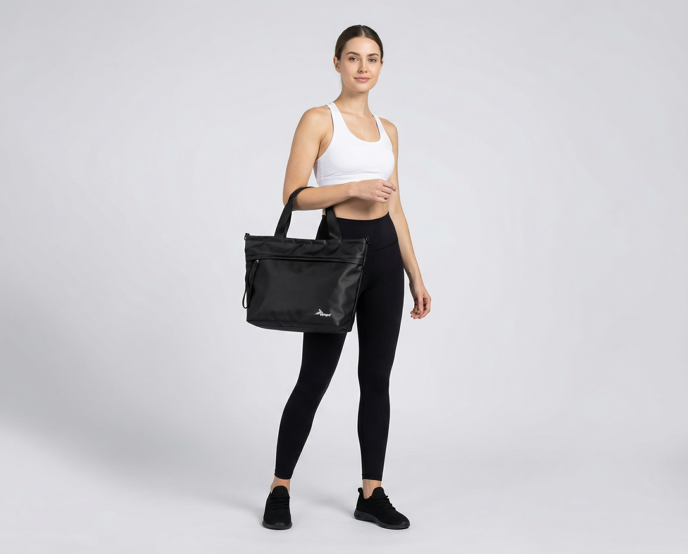 Woman holding a black tote bag against a white background